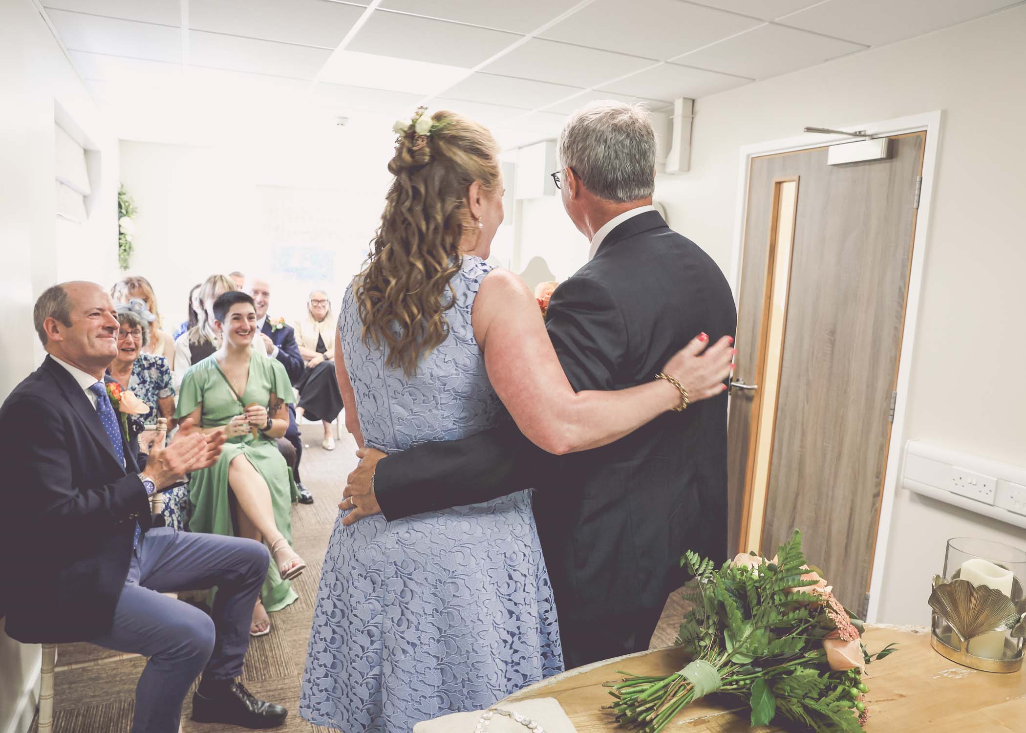 A bride and groom from behind with arms round each other on a wedding day in Woodbridge captured by Suffolk Wedding Photographer Hayley Denston Photography